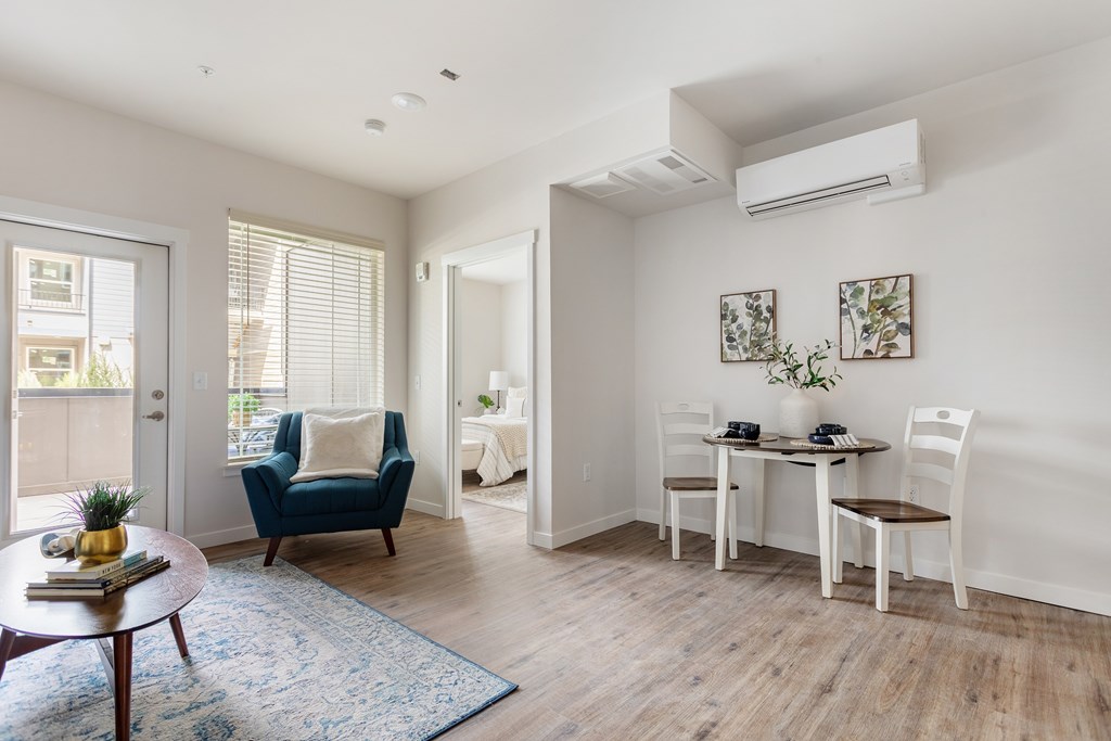 A living room with a blue chair and a small table with a plant on it.