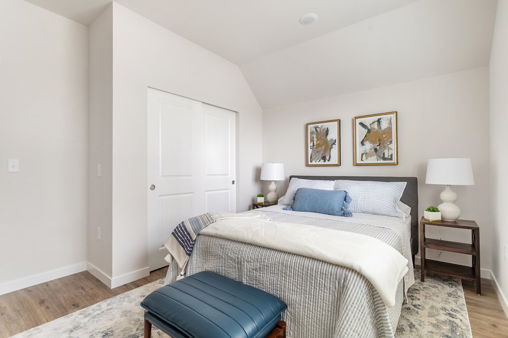 A bedroom with a bed, nightstand, and two wall art pieces.