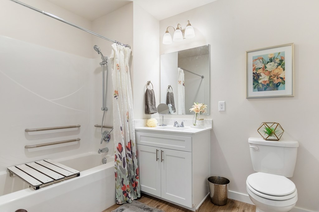 A white bathroom with a floral shower curtain and a white toilet.