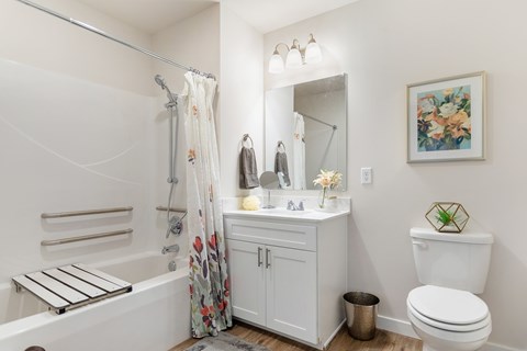 A white bathroom with a floral shower curtain and a white toilet.