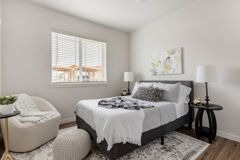 A bedroom with a large bed, a chair, and a small table.