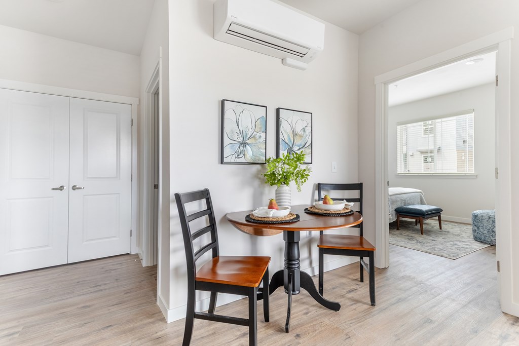 A dining room with a table set for two and a plant on the table.