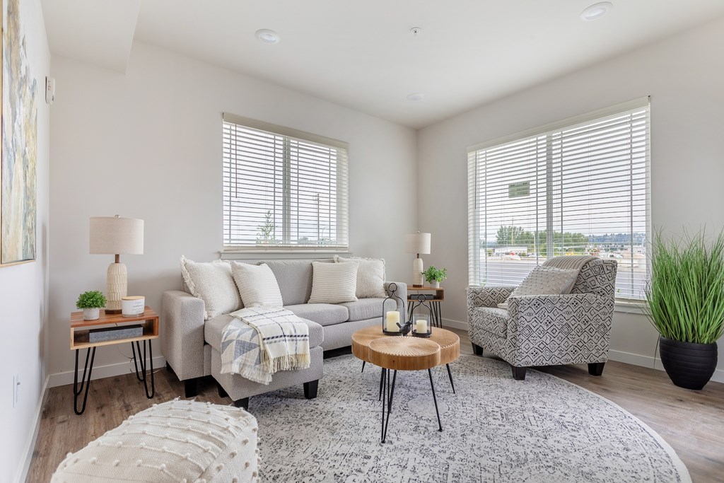 A living room with a grey couch, a wooden table, and a rug.