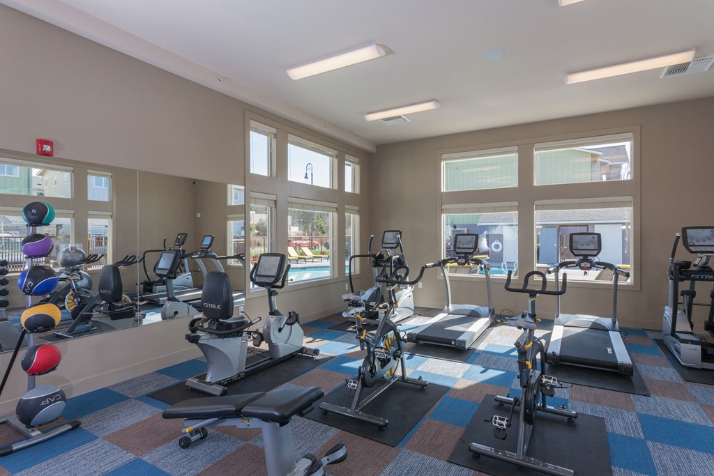 a gym with treadmills and other exercise equipment in a building with windows