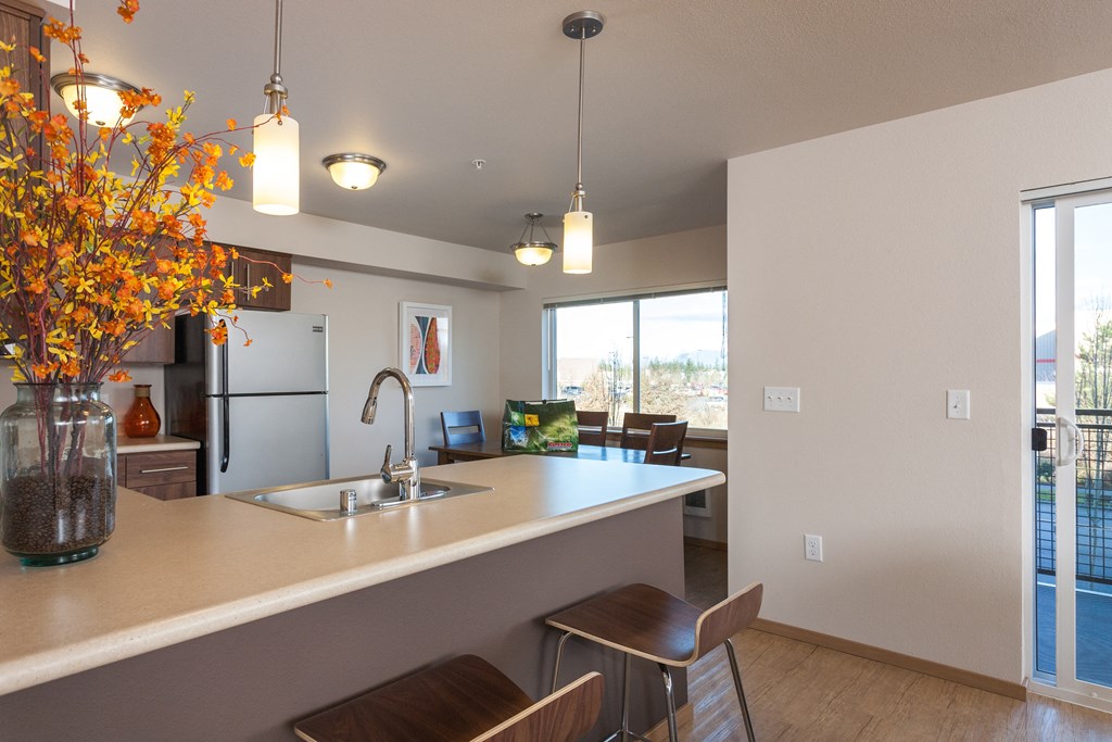 the view of a kitchen and living room from behind a counter with a sink