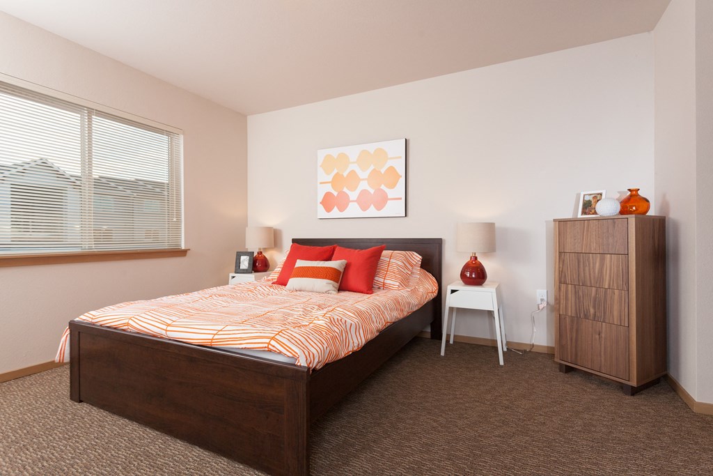 a bedroom with a bed and a dresser and a window