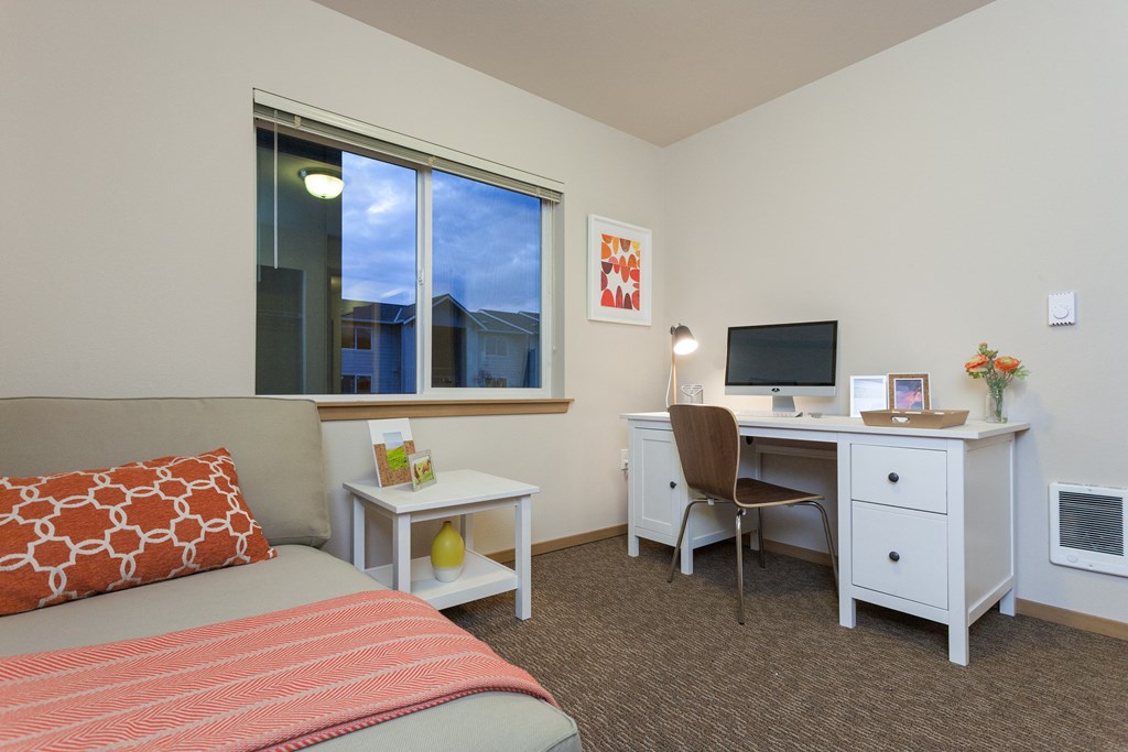 a bedroom with a bed and a desk with a computer