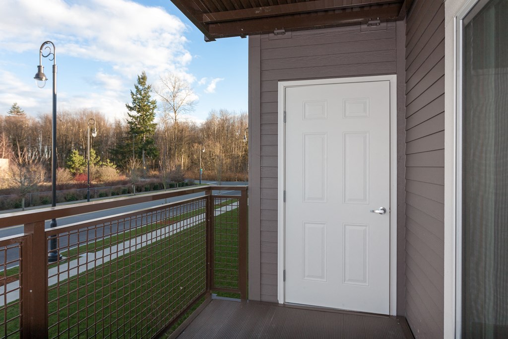 a porch with a white door and a deck with a fence