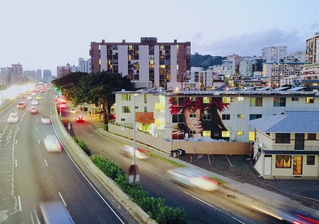 A busy street with cars and buildings at dusk.