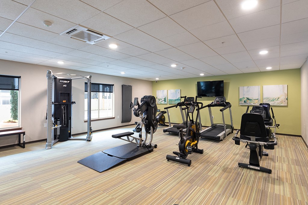 a gym with weights and cardio equipment on a wooden floor
