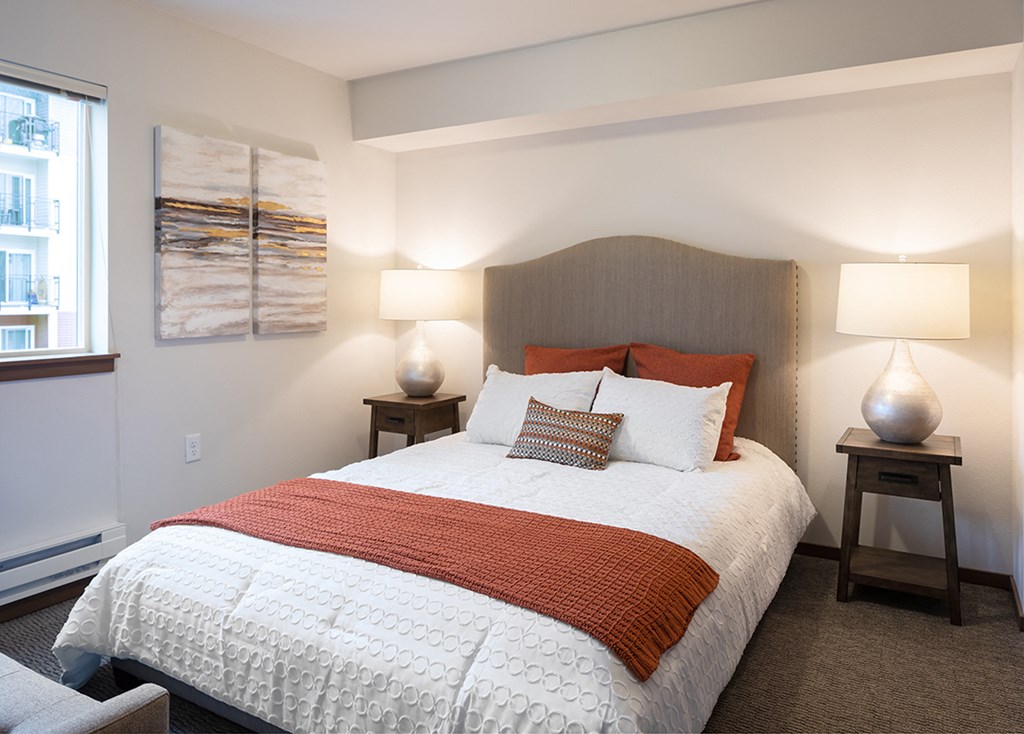 a bedroom with a bed and two lamps and a window