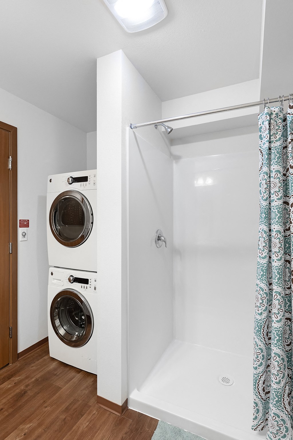 a washer and dryer in a bathroom next to a shower and a door