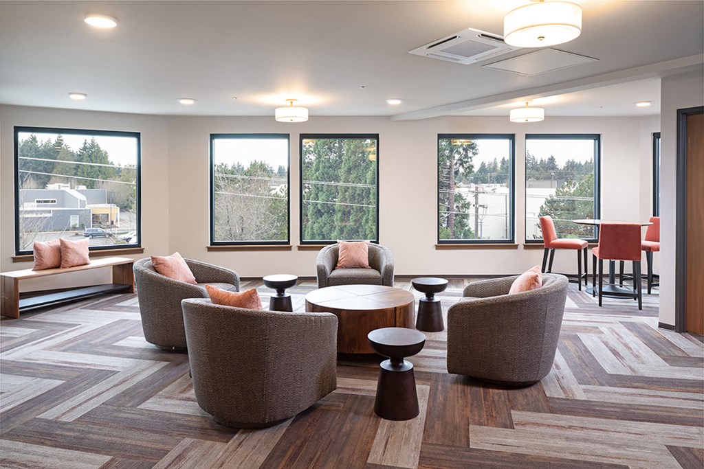 a lounge area with chairs and tables in a room with windows