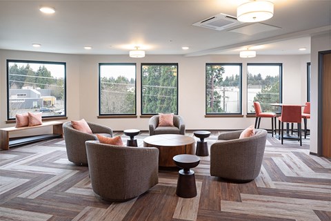 a lounge area with chairs and tables in a room with windows