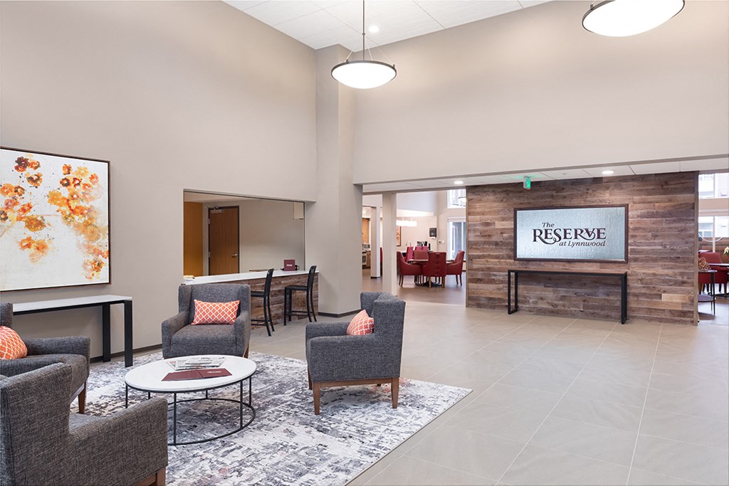 a lobby with chairs and tables and a fireplace