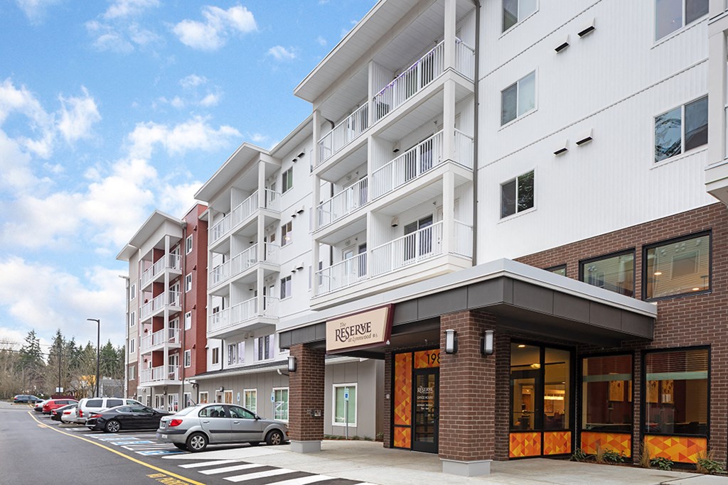 a rendering of a new apartment building with cars parked outside