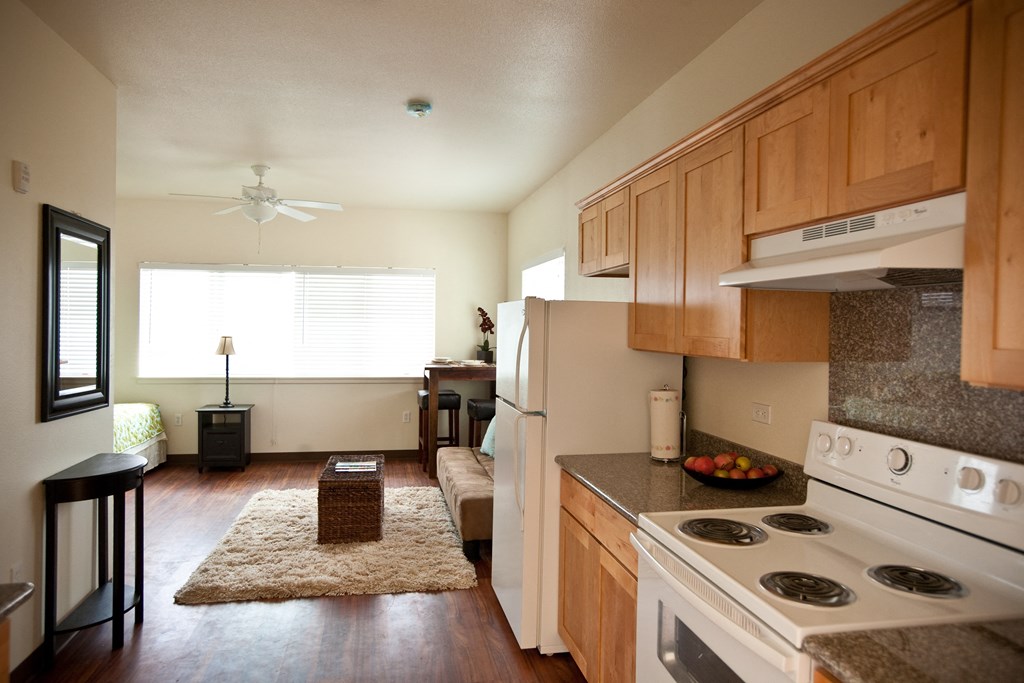 an open kitchen and living room with a white stove and refrigerator