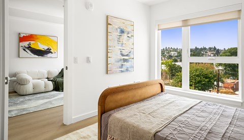 A bedroom with a large bed and a painting on the wall.