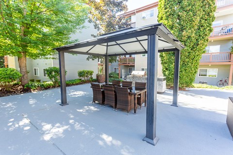 a patio with a table and chairs under a gazebo