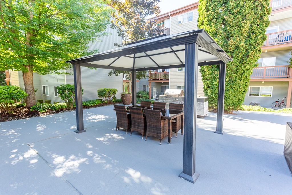 a patio with a table and chairs under a gazebo