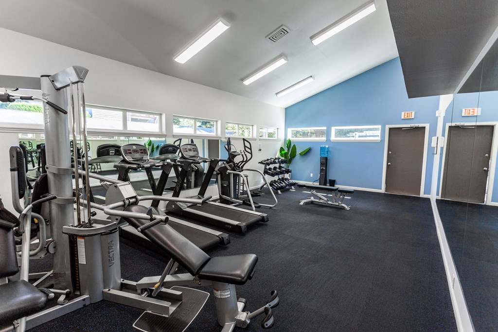 a gym with cardio equipment on the floor and windows