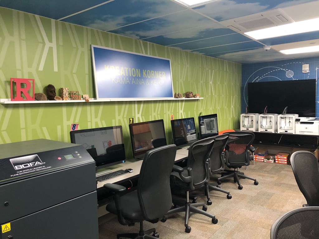 a computer room with several desks and chairs and a projector screen