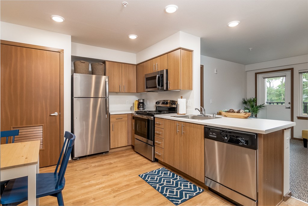 a kitchen with wooden cabinets and stainless steel appliances and a white counter top