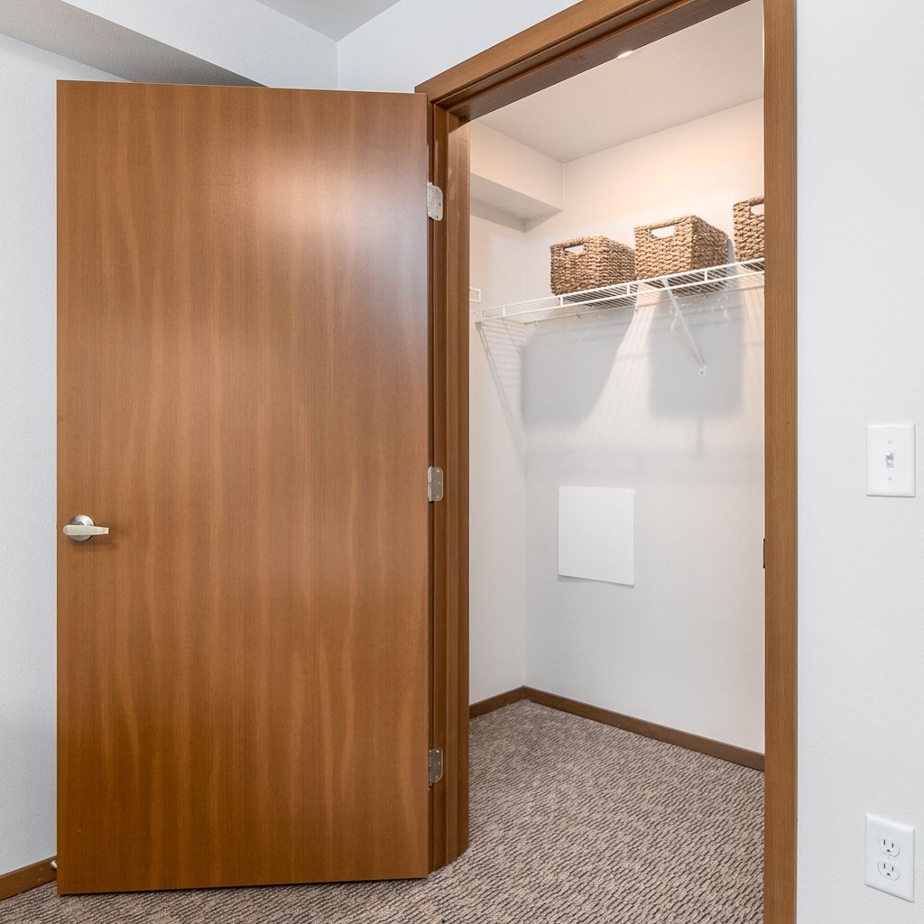 a door to a closet in a room with a white wall