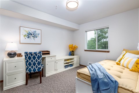 a bedroom with a bed and a desk and a window