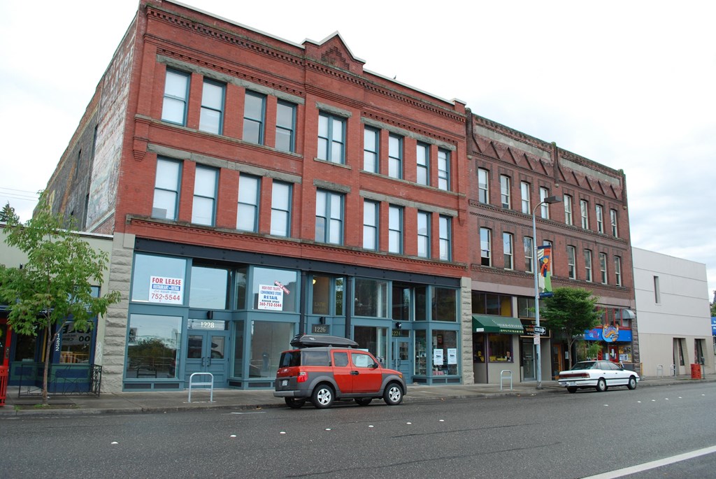a red brick building on a city street with a car parked in front of it