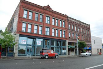 a red brick building with a small red suv parked in front of it