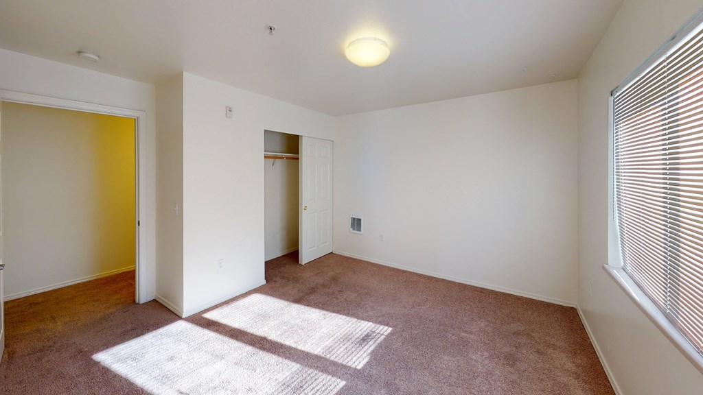 an empty living room with a window and a door to a closet