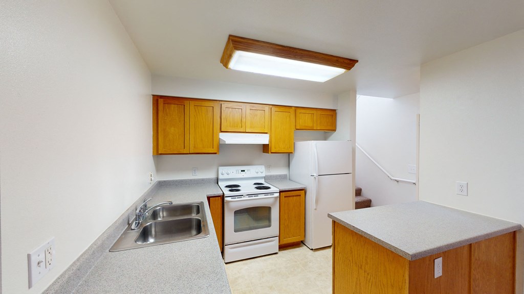 an empty kitchen with white appliances and wooden cabinets