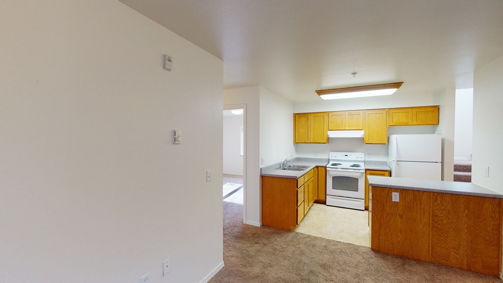 an empty kitchen with white appliances and wooden cabinets