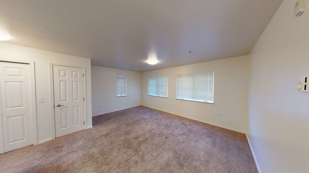 an empty living room with a white door and a window