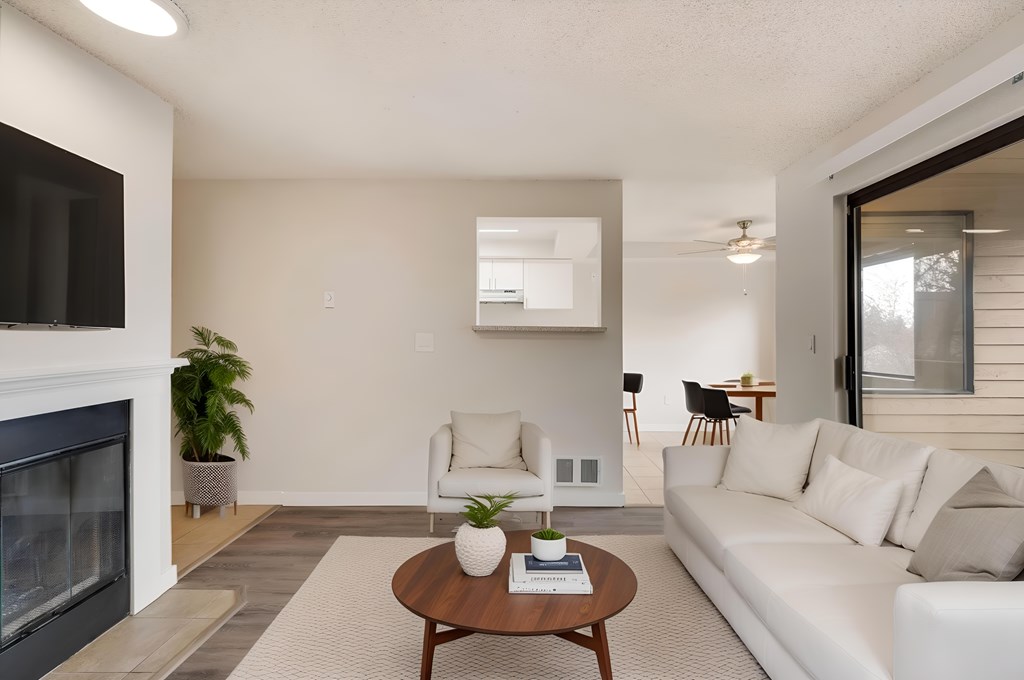 A modern living room with a fireplace, a white sofa, and a wooden coffee table.