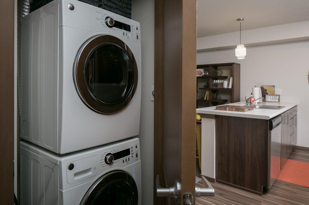 a front loading washer and dryer in a laundry room next to a kitchen