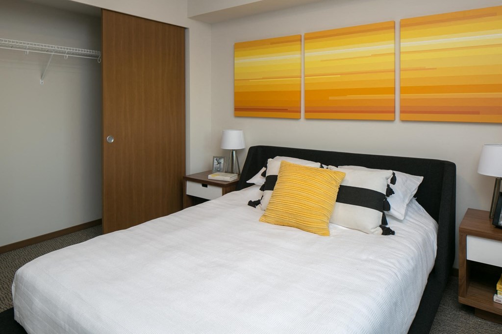 a bedroom with a bed and three orange paintings on the wall