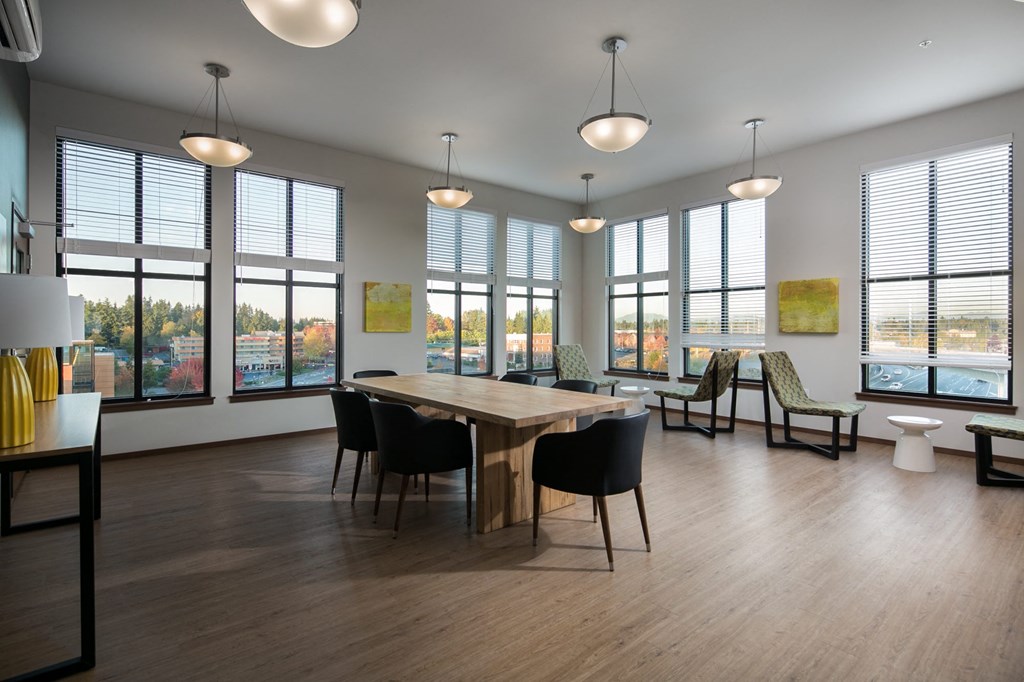 a living room with a table and chairs and large windows