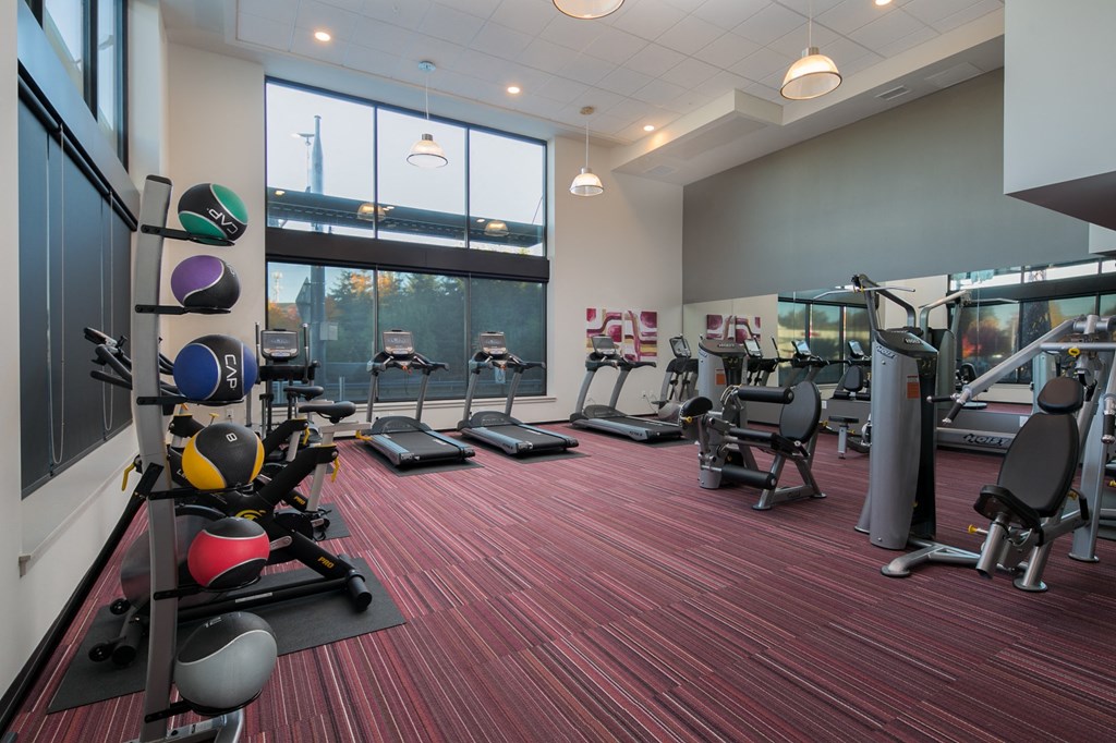 a gym with treadmills and other exercise equipment in a building with large windows