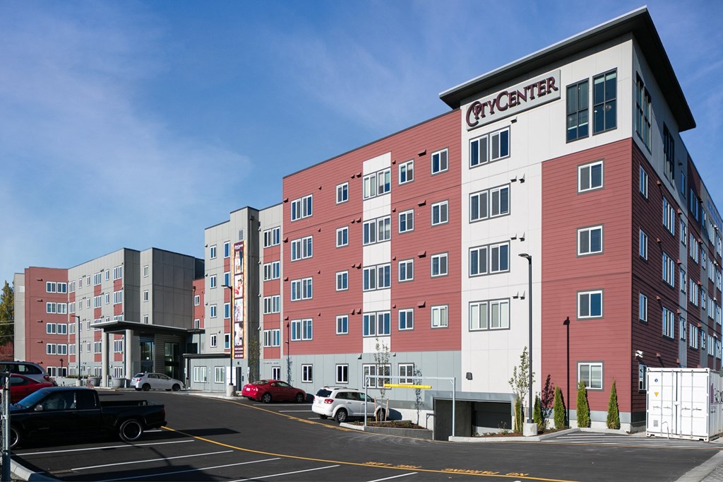 a large red and white apartment building with cars parked in front of it
