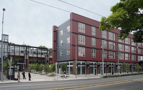 A red building with a glass entrance and a street in front.