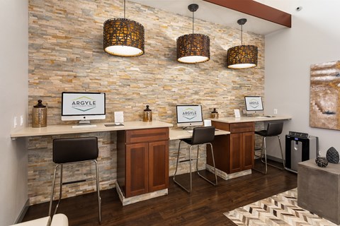 A modern office space with a stone wall and a desk with a computer.
