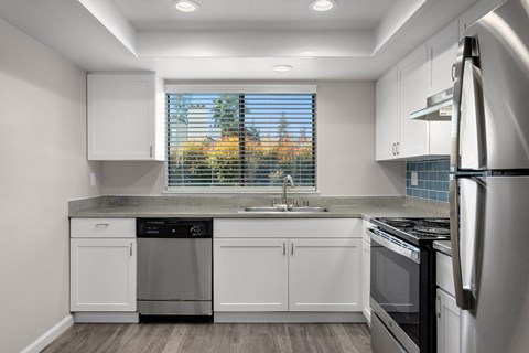 A modern kitchen with white cabinets and stainless steel appliances.