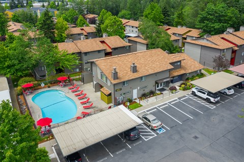 A swimming pool surrounded by red chairs and a building in the background.