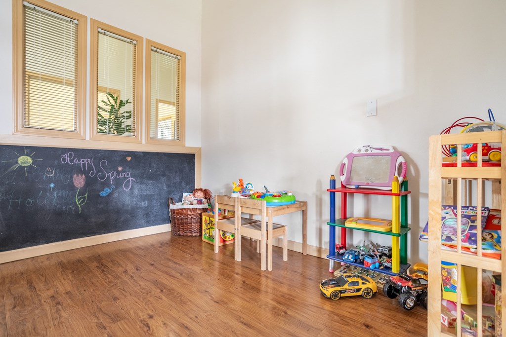 a childs play room with a chalkboard and desks and toys