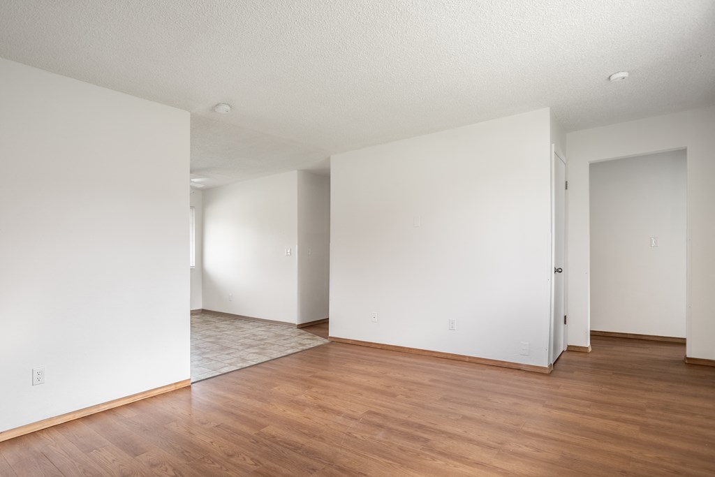 an empty living room with wood floors and white walls