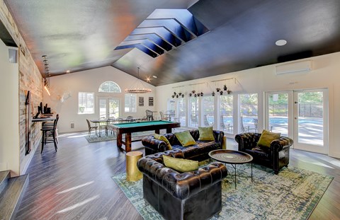 A living room with a black couch and a blue rug.