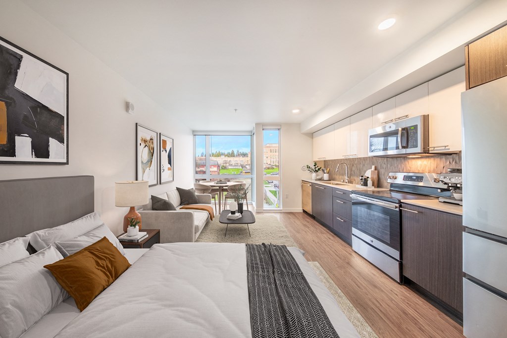 a living room with a couch and a bed and a kitchen with a sink