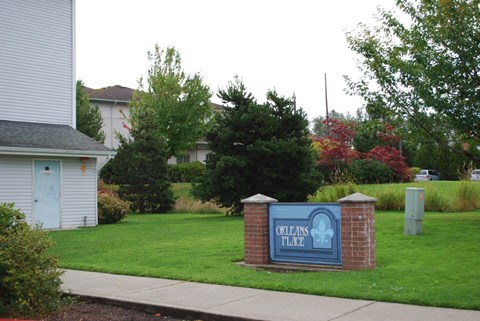 A sign that says "Orleans Place" is in front of a grassy area.